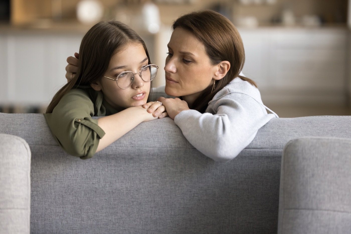 En forælder trøster sin teenager på sofaen